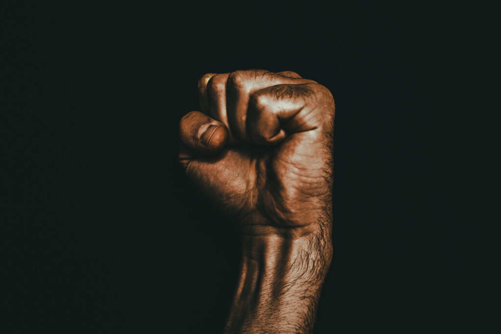 Male black fist on a black background. Aggressiveness, masculinity, the concept of challenge.